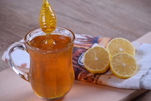 A glass of honey syrups, with slices of lemon on the side