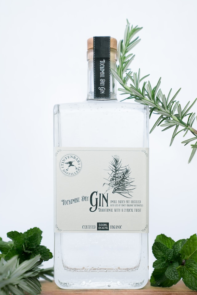 A bottle of gin with herbs around it