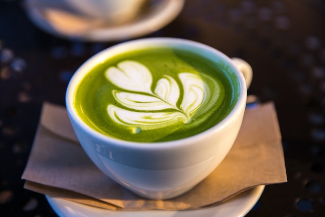 A cup of green tea latte topped with a decorative art 