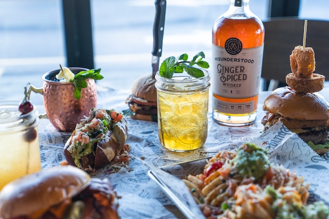 A table with an assortment of cocktails, a bottle of whiskey and food