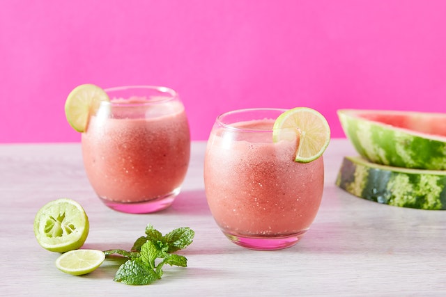 Pink colored liquid inside two clear glasses garnished with slices of lemon