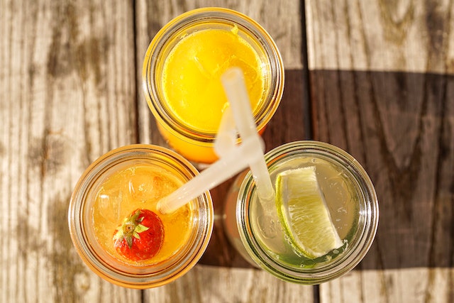 An assortment of fruit juices inside three clear glasses