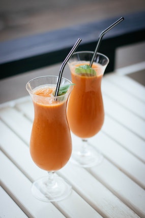 Orange-looking fruit juice inside two clear glasses