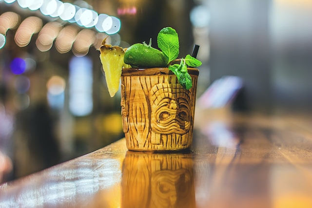 Quirky cocktail mug garnished with mint leaves, pineapple slice, and lime