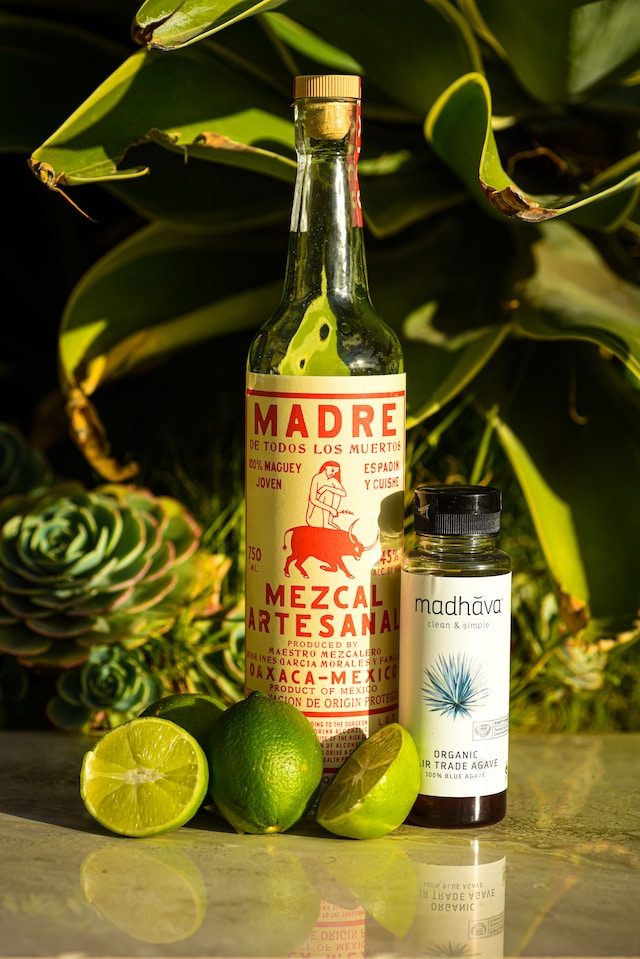A bottle of Mexican spirit, agave, and limes