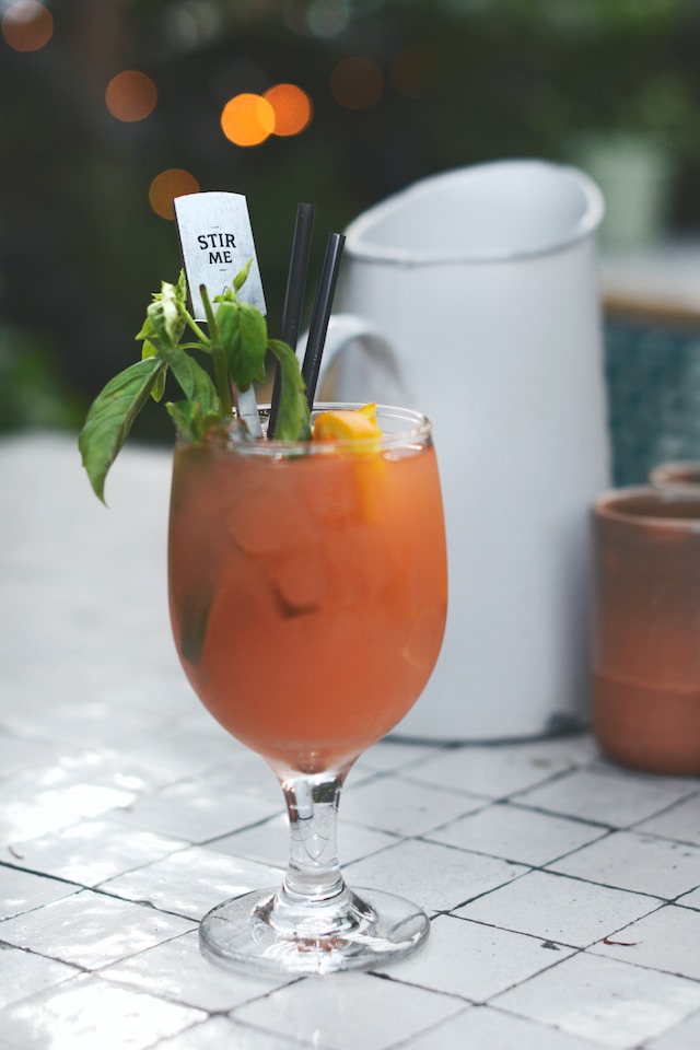 Orange colored drink garnished with basil leaves