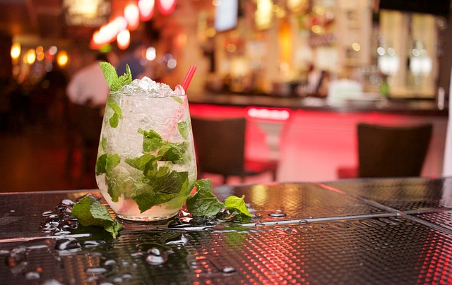 Clear drink with mint leaves in a glass with a red straw