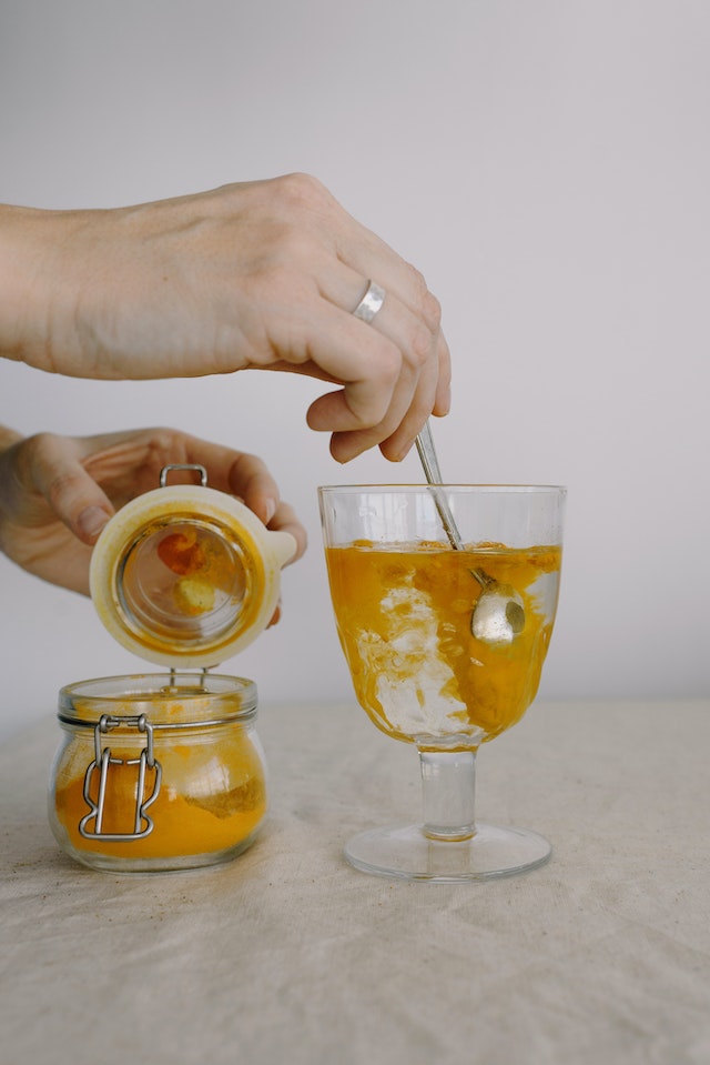 Person adding turmeric powder to a drink